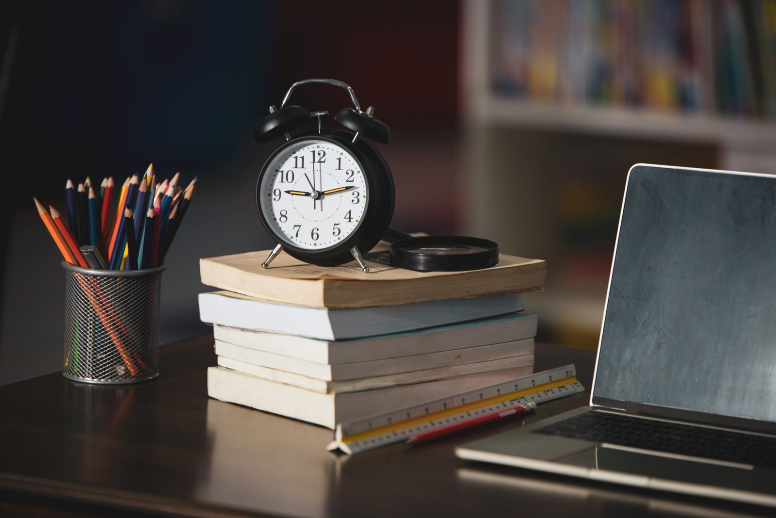 Book,laptop,pencil,clock on wooden table in library,education le